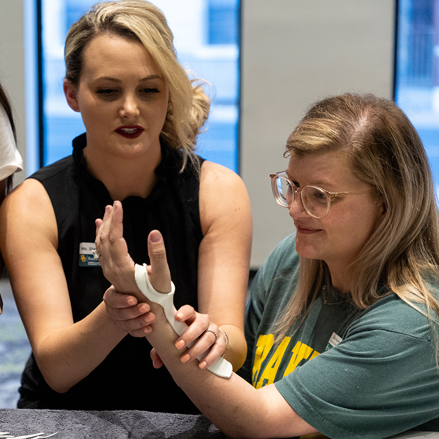 Occupational therapy student practicing splinting on another student.