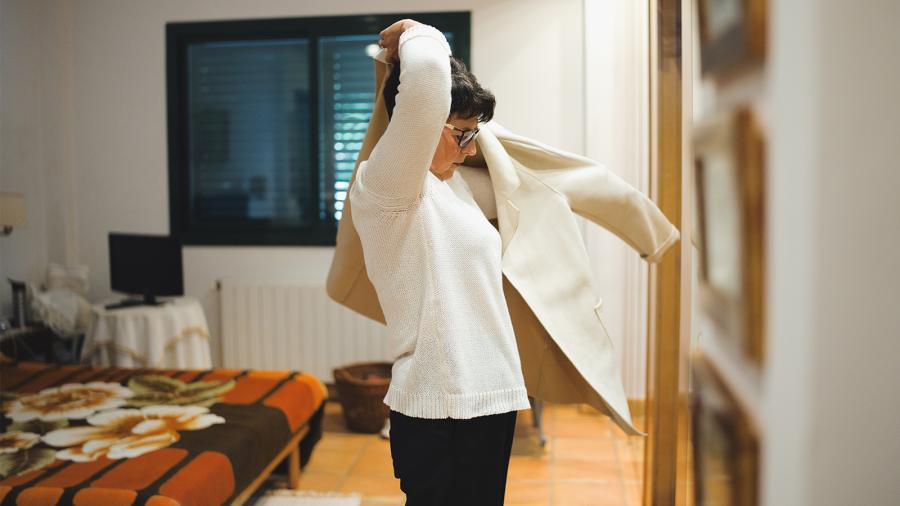 Woman puts on a jacket to wear.