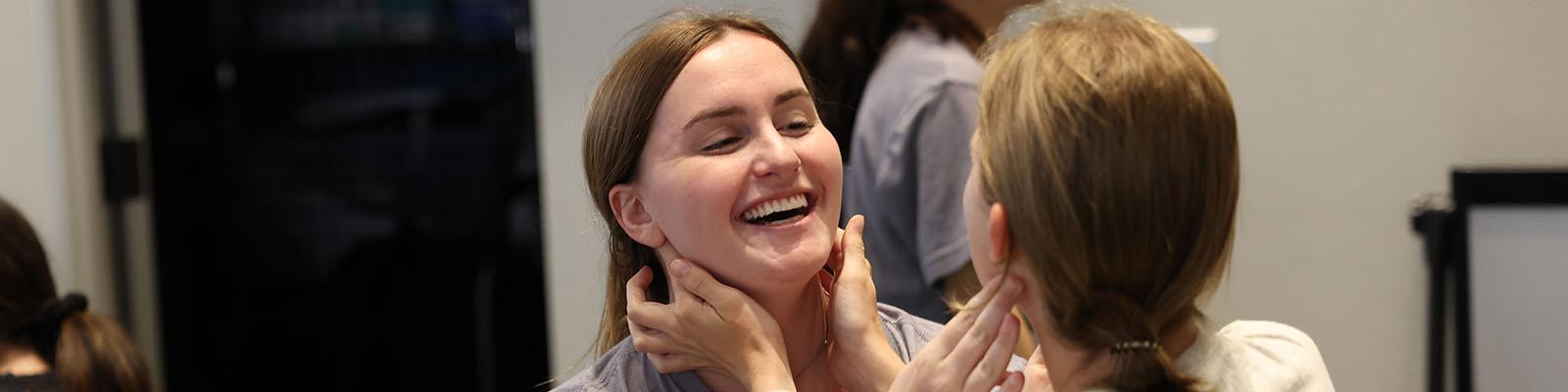 Two students practicing a technique on each other's necks and smiling during the Human Movement lab immersion.