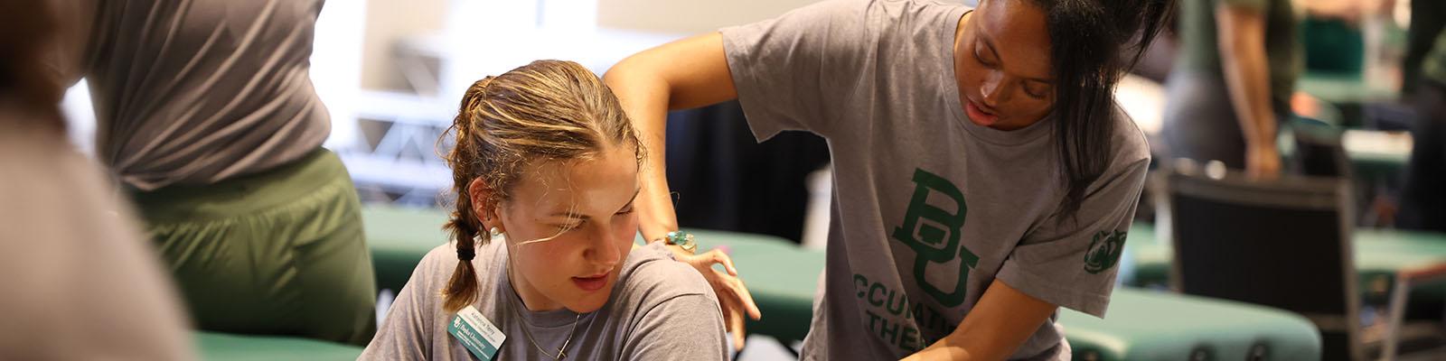 A student practices a technique on a sitting student during the Human Movement lab immersion