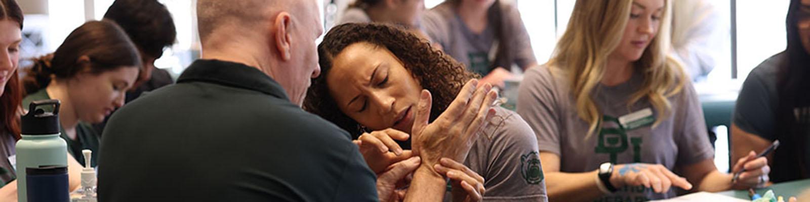 A student practices a technique on a professor during an Occupational Therapy lab immersion.