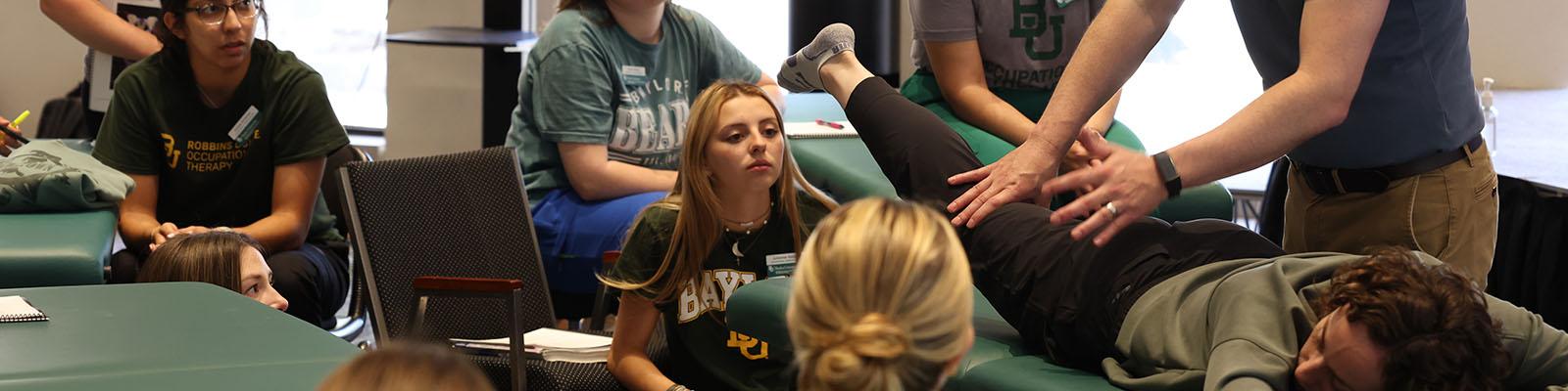 Occupational therapy students watch a lab demonstration on a student showing human movement